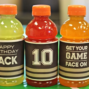 Puede incluir: Tres botellas de pl&aacute;stico transparentes con tapas naranjas y etiquetas en blanco y negro. Las etiquetas tienen el texto "Happy Birthday Jack", "10" y "Get Your Game Face On".