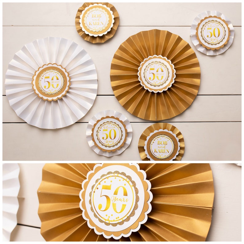 May include: Gold and white paper fans with gold glitter and the number 50 on them. Some fans say "Bob and Karen" and "50 Years".
