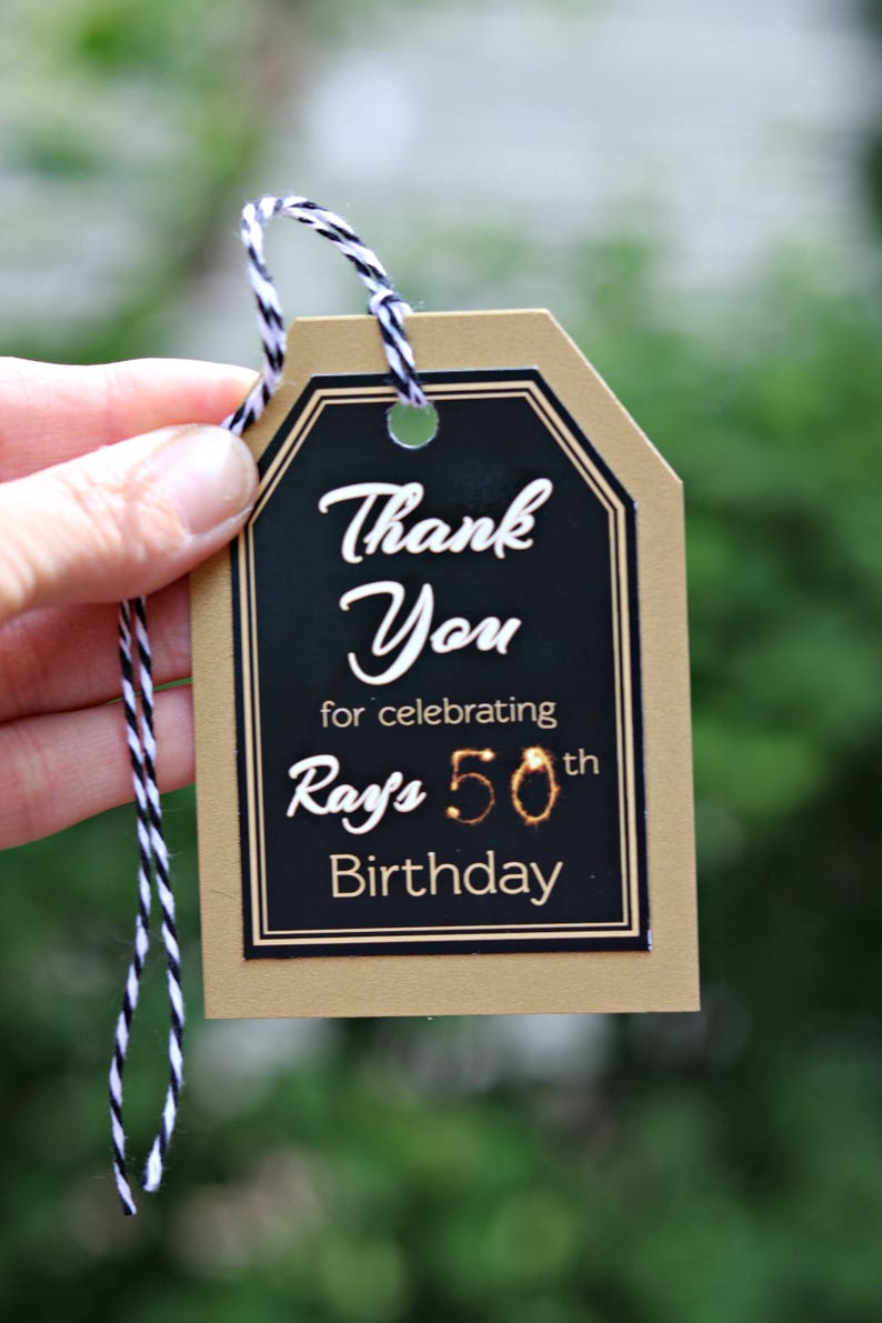 May include: A gold and black thank you tag with the text "Thank You for celebrating Ray's 50th Birthday".