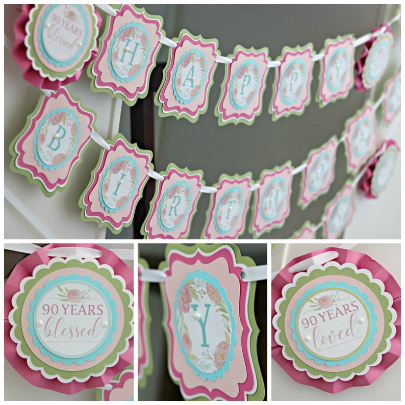 May include: A pink, green, and blue "Happy Birthday" banner with floral accents and the text "90 Years Blessed". The banner is strung with white ribbon and features scalloped edges.