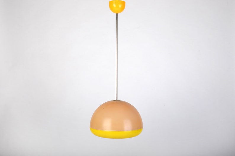 Może przedstawiać: Lampa wisząca z kloszem w kształcie kopuły w kolorze brzoskwiniowym i ż&oacute;łtym pasem wok&oacute;ł dolnej części. Lampa jest zawieszona na srebrnym sznurze.