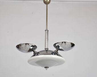 May include: A vintage chrome and white glass pendant light fitting. The light has a central white glass shade and two chrome-finished, bowl-shaped lights. The fitting is suspended from a metal rod and ceiling mount.