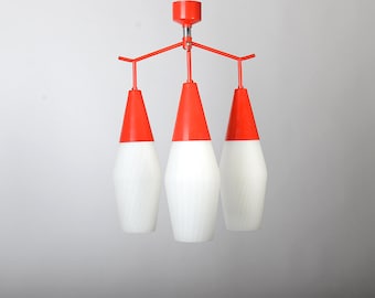 May include: A red and white ceiling light fixture with four cone-shaped shades. The shades are white on the bottom and red on the top.