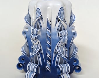 May include: A white and blue hand-carved candle with a swirl design. The candle is decorated with intricate details and has a blue and white ombre effect.