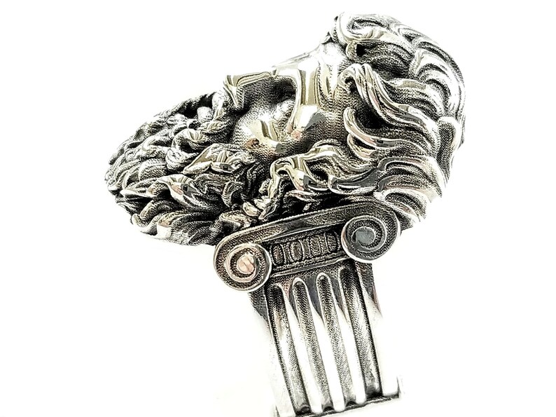 A large silver ring featuring the powerful figure of Zeus, the king of the gods, intricately carved atop a sturdy band.  Flanked by majestic Greek columns on each side, this bold statement piece exudes strength, sophistication, and timeless appeal.