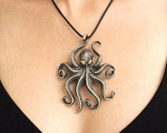 Silver octopus pendant on black leather cord, textured skin with garnet eyes