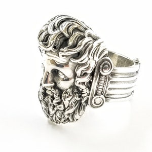 A large silver ring featuring the powerful figure of Zeus, the king of the gods, intricately carved atop a sturdy band.  Flanked by majestic Greek columns on each side, this bold statement piece exudes strength, sophistication, and timeless appeal.