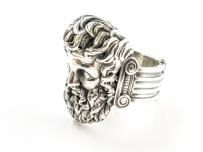 A large silver ring featuring the powerful figure of Zeus, the king of the gods, intricately carved atop a sturdy band.  Flanked by majestic Greek columns on each side, this bold statement piece exudes strength, sophistication, and timeless appeal.