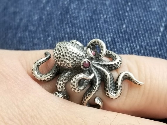 Tiny octopus ring in sterling silver 925 with garnets.
The silver octopus ring is handmade with entangled, intertwining octopus tentacles.
The octopus eyes on the statement ring are set with garnet gemstones.