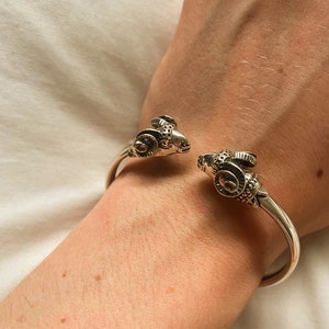 A ram head bracelet in solid silver 925.
The silver ram bracelet consists of two silver ram heads on a silver torc tube.
The ram bracelet is handmade and has a beautiful oxidation giving a contrast to the ram horns and ram head details.