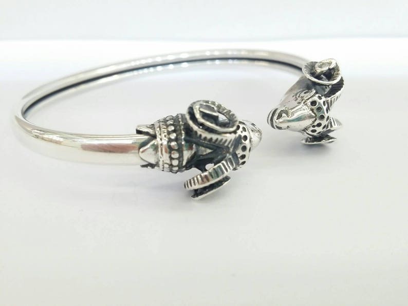 A ram head bracelet in solid silver 925.
The silver ram bracelet consists of two silver ram heads on a silver torc tube.
The ram bracelet is handmade and has a beautiful oxidation giving a contrast to the ram horns and ram head details.