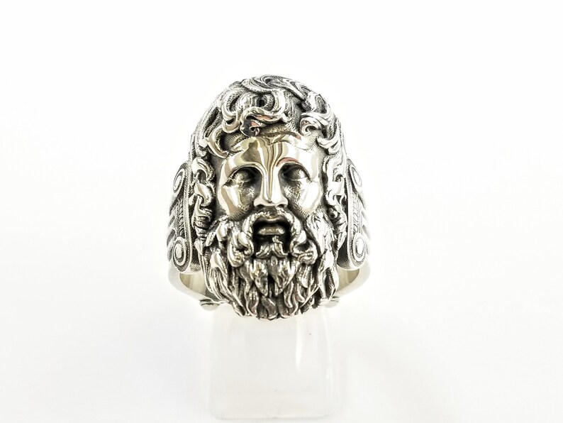 A large silver ring featuring the powerful figure of Zeus, the king of the gods, intricately carved atop a sturdy band.  Flanked by majestic Greek columns on each side, this bold statement piece exudes strength, sophistication, and timeless appeal.