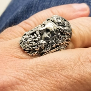A large silver ring featuring the powerful figure of Zeus, the king of the gods, intricately carved atop a sturdy band.  Flanked by majestic Greek columns on each side, this bold statement piece exudes strength, sophistication, and timeless appeal.