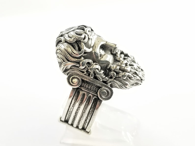 A large silver ring featuring the powerful figure of Zeus, the king of the gods, intricately carved atop a sturdy band.  Flanked by majestic Greek columns on each side, this bold statement piece exudes strength, sophistication, and timeless appeal.