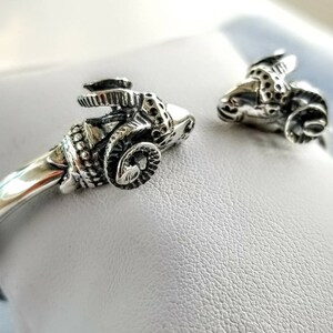 A ram head bracelet in solid silver 925.
The silver ram bracelet consists of two silver ram heads on a silver torc tube.
The ram bracelet is handmade and has a beautiful oxidation giving a contrast to the ram horns and ram head details.