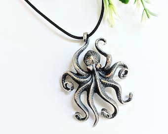 Silver octopus pendant on black leather cord, textured skin with garnet eyes