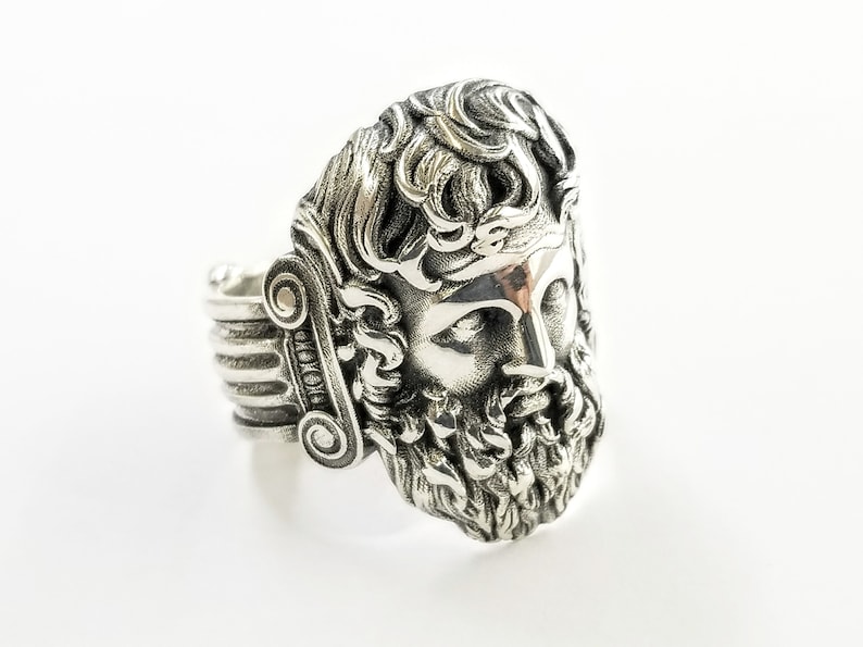 A large silver ring featuring the powerful figure of Zeus, the king of the gods, intricately carved atop a sturdy band.  Flanked by majestic Greek columns on each side, this bold statement piece exudes strength, sophistication, and timeless appeal.