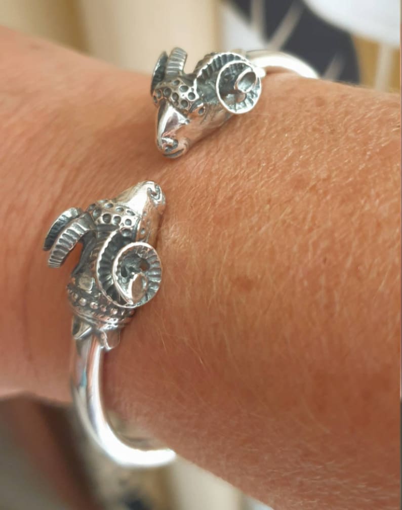 A ram head bracelet in solid silver 925.
The silver ram bracelet consists of two silver ram heads on a silver torc tube.
The ram bracelet is handmade and has a beautiful oxidation giving a contrast to the ram horns and ram head details.