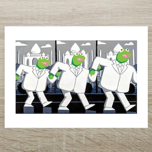 May include: An art print showing three Kermit the Frog characters in white suits, walking in step. The background is a grey cityscape with white buildings. The artwork has a playful and humorous theme.
