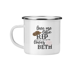 Op de afbeelding: Een witte emaille mok met een zilveren rand. De mok heeft een bruine cowboyhoed, prikkeldraad en een roze bloem met de tekst "love me like RIP loves BETH".