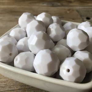 May include: A bowl filled with white silicone beads. The beads are faceted and have a matte finish.