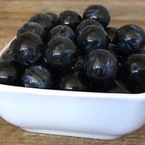 May include: A white bowl filled with black and white marbled round beads.