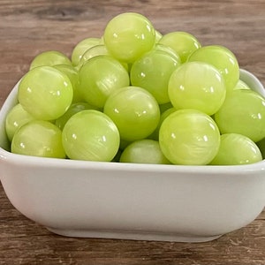 May include: A white bowl filled with light green iridescent marbles.