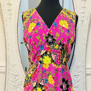 May include: A sleeveless pink dress with a paisley print in shades of black, green, yellow, and blue. The dress has a V-neckline and a fitted bodice.
