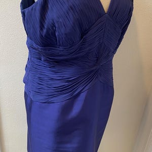 May include: A sleeveless royal blue dress with a pleated bodice and a fitted skirt. The bodice has a V-neckline and a gathered detail at the waist.