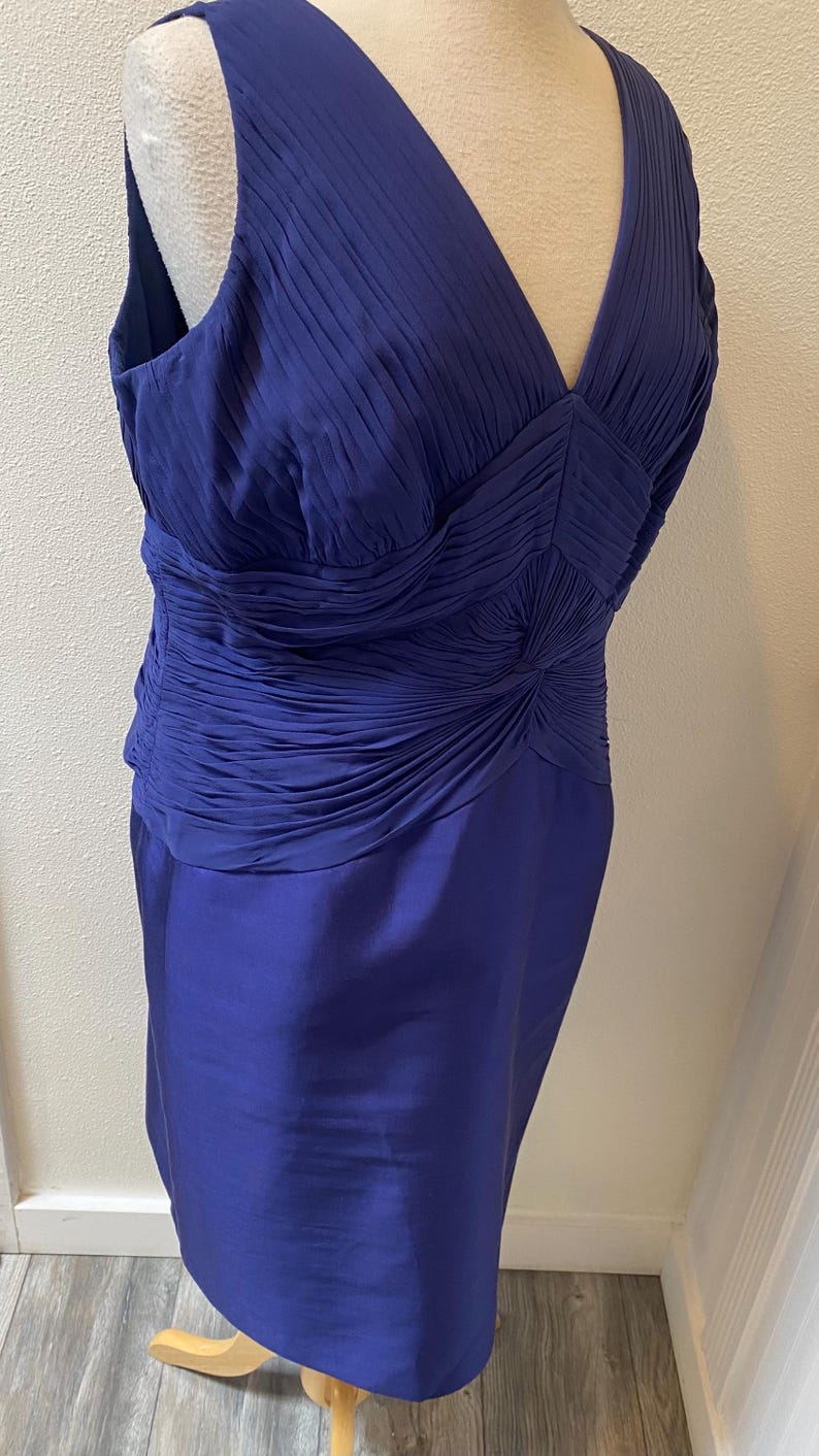May include: A sleeveless royal blue dress with a pleated bodice and a fitted skirt. The bodice has a V-neckline and a gathered detail at the waist.