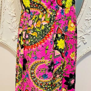 May include: A pink maxi dress with a floral paisley print. The dress has a V-neckline and sleeveless design.