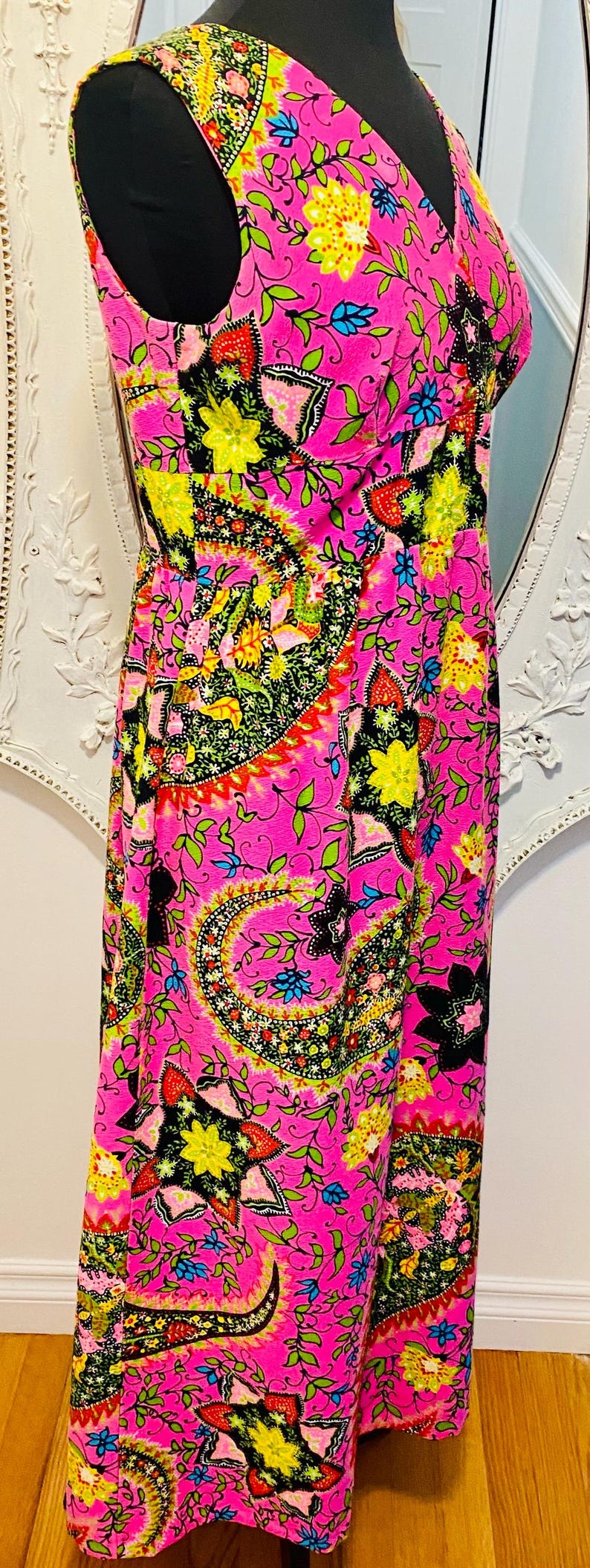 May include: A pink maxi dress with a floral paisley print. The dress has a V-neckline and sleeveless design.