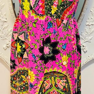 May include: A pink sleeveless maxi dress with a paisley print in shades of green, yellow, black, and blue.