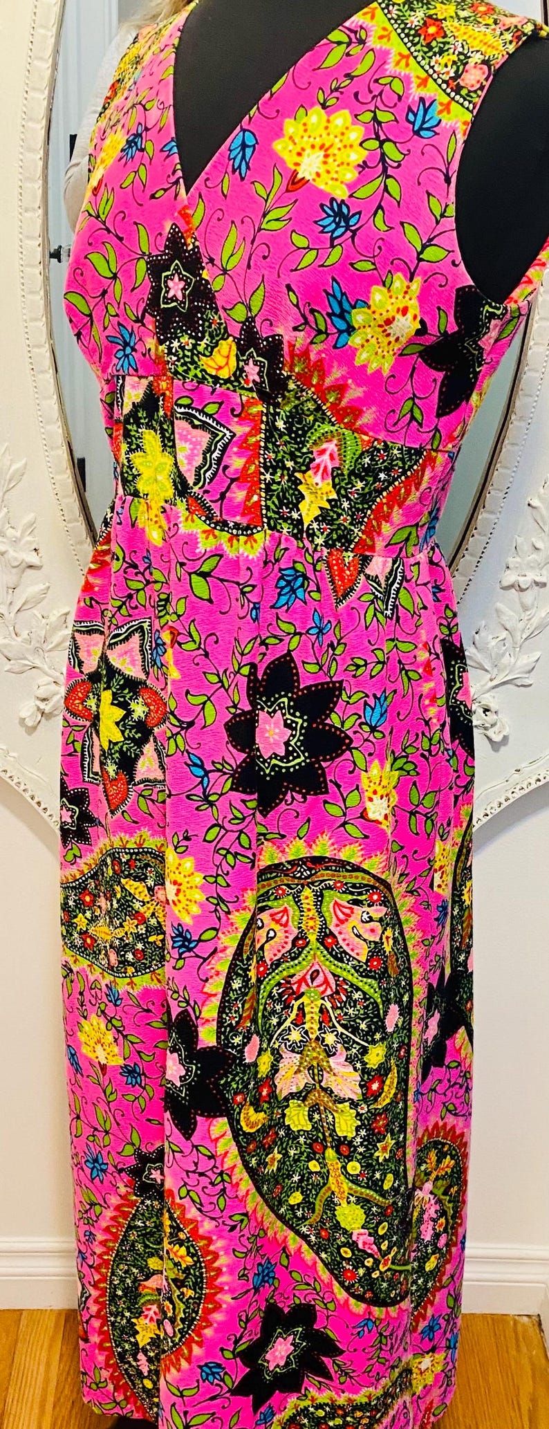 May include: A pink sleeveless maxi dress with a paisley print in shades of green, yellow, black, and blue.