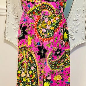 May include: A sleeveless maxi dress with a pink background and a colorful paisley pattern. The dress has a fitted bodice and a flowing skirt.