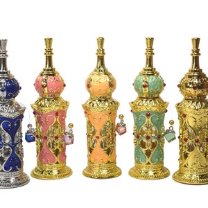 May include: Five ornate perfume bottles in various colors: blue, pink, orange, green, and gold. Each bottle features intricate gold detailing, jewel accents, and a small hanging charm. The bottles have a decorative, elongated shape.