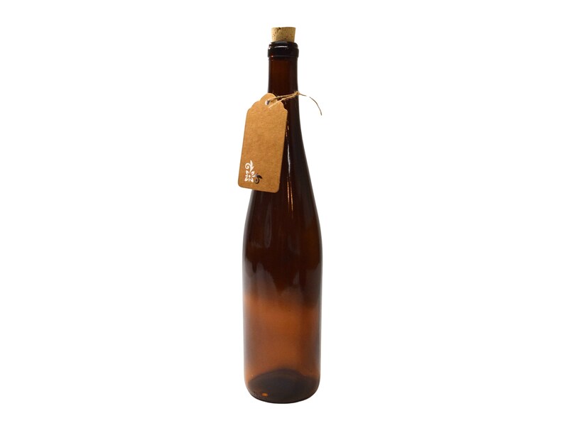 Puede incluir: Una botella de vidrio marr&oacute;n con un tap&oacute;n de corcho y una etiqueta de papel marr&oacute;n atada alrededor del cuello. La etiqueta tiene texto blanco que dice "The Little Seed".
