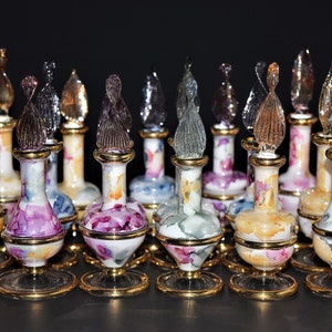 May include: A collection of decorative glass bottles with colorful floral designs and gold accents. The bottles have clear glass stoppers with intricate designs.