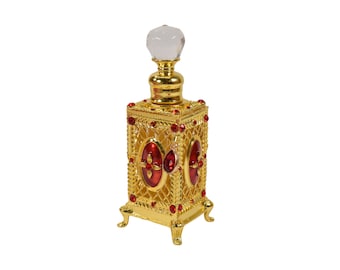 May include: A gold perfume bottle with red jeweled accents and a clear glass stopper. The bottle has a square shape with ornate detailing and sits on four small feet.