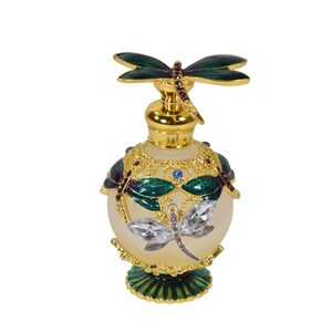 May include: A gold and green glass perfume bottle with a dragonfly design. The bottle has a round body and a decorative base.