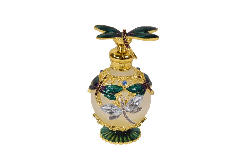 May include: A gold and green glass perfume bottle with a dragonfly design. The bottle has a round body and a decorative base.