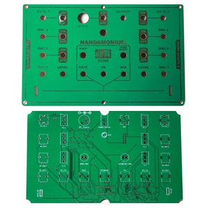 Könnte beinhalten: Eine grüne Leiterplatte mit dem aufgedruckten Text "NANDAMONIUM". Die Platine verfügt über eine Vielzahl von Knöpfen, Schaltern und Buchsen. Der Text "HAND SYNTH 2" ist auf der rechten Seite der Platine aufgedruckt.