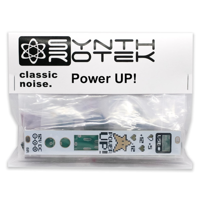 May include: A white circuit board with green and gold accents, packaged in a clear plastic bag. The board has the text "Power UP!" and "USB" printed on it. The package also features the "Synthrotek" logo and the words "classic noise."