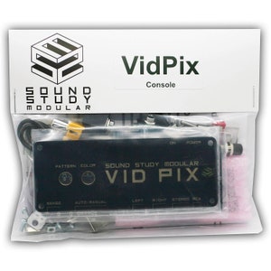 May include: A black VidPix console by Sound Study Modular, packaged in a clear plastic bag. The console has buttons and ports, with the text "VidPix" and "Console" visible. The package also contains various cables and components.