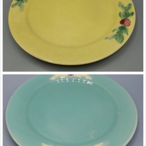 May include: Two ceramic plates with floral designs. The top plate is yellow with green leaves and pink flowers. The bottom plate is teal with yellow leaves and pink flowers.