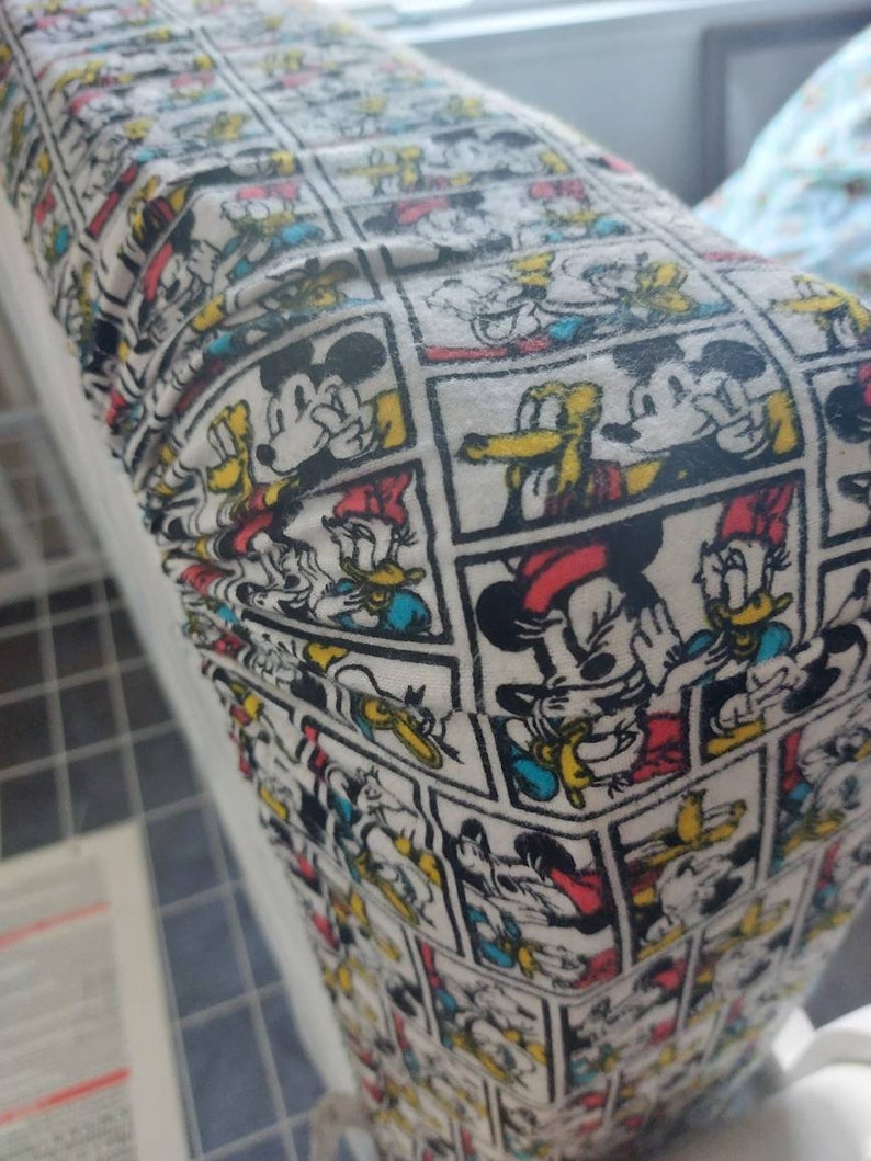 May include: White fabric with a repeating pattern of Mickey Mouse and Donald Duck cartoon characters in comic book panels. The characters are in black, red, yellow, and blue.