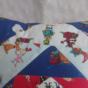 Peut inclure: Un coussin en patchwork color&eacute; repr&eacute;sentant des personnages du livre "Comment le Grinch a vol&eacute; No&euml;l !" Le coussin est fait de diff&eacute;rents tissus, dont du rouge, du bleu, du blanc et du vert. Le coussin est d&eacute;cor&eacute; de divers personnages, dont le Grinch, Cindy Lou Who et Max le chien.