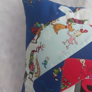 Peut inclure: Une housse de coussin en patchwork bleu et blanc sur le th&egrave;me de No&euml;l. Le tissu pr&eacute;sente une vari&eacute;t&eacute; de personnages du livre "Comment le Grinch a vol&eacute; No&euml;l !" dont le Grinch, Cindy Lou Who et Max le chien.