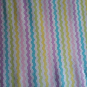 May include: A white fabric with a wavy striped pattern in shades of light blue, green, pink, and purple.