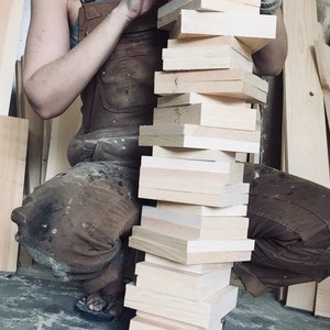 Artist holding raw wood blanks used to craft coastal and beach-themed tissue box covers, showcasing handmade, Maine-crafted process for nautical, seaside, and rustic home décor. Highlights craftsmanship, quality materials, and rustic finishing for cabins, beach houses, and lake homes